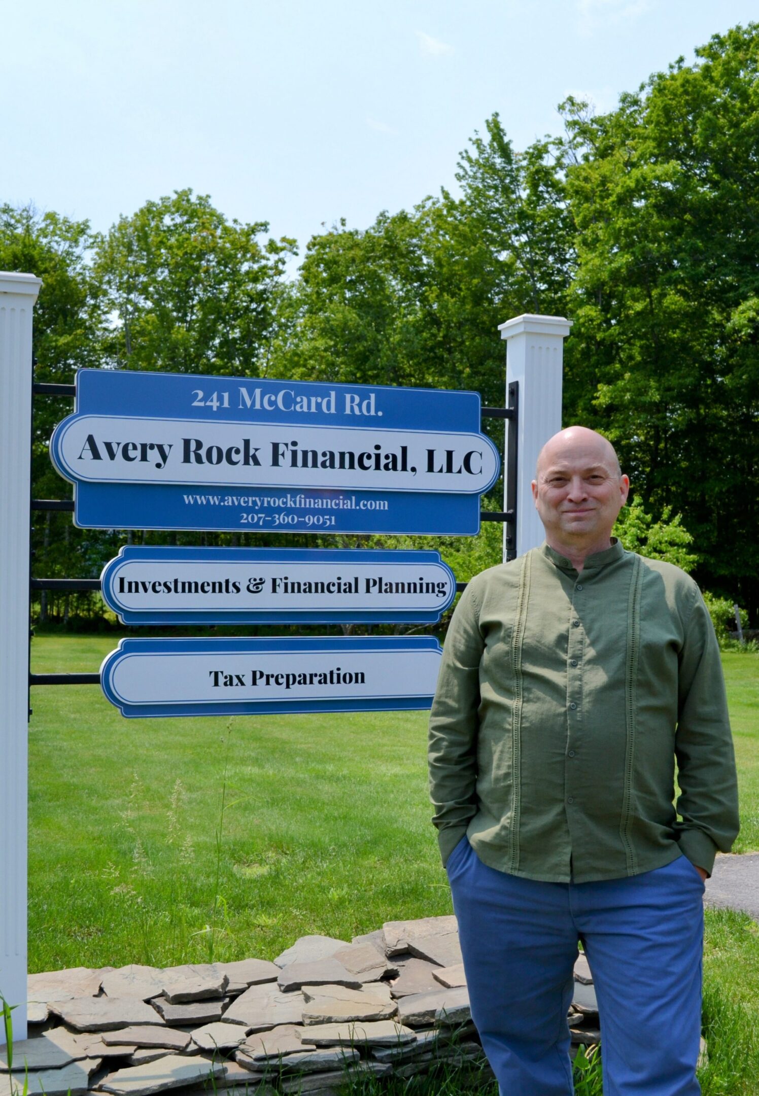 Man standing beside Avery Rock Financial sign.